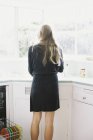 Mulher de pé em uma pia da cozinha . — Fotografia de Stock