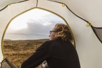 Homem sentado no abrigo de uma tenda — Fotografia de Stock
