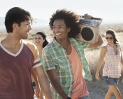 Friends walking on the open road with a boombox. — Stock Photo
