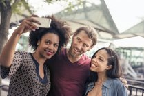 Homme et deux femmes, prendre des selfies dans le parc — Photo de stock