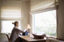 Donna seduta ad una scrivania vicino ad una finestra — Foto stock