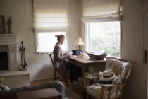 Donna seduta ad una scrivania vicino ad una finestra — Foto stock