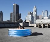Coppia in piscina gonfiabile sul tetto di una città — Foto stock