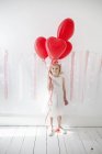 Chica joven sosteniendo globos rojos . - foto de stock