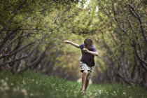 Ребенок бежит вдоль дуги ветвей дерева — стоковое фото