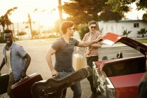 Friends packing the car with suitcases and a guitar — Stock Photo