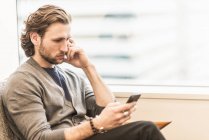 Bearded man sitting frowning — Stock Photo