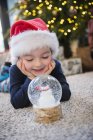 Мальчик со стеклянным снежным шаром — стоковое фото
