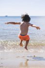 Boy jumping over waves — Stock Photo