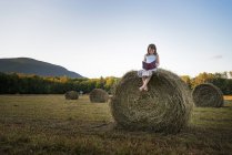 Girl sitting on the top of bale. — Stock Photo