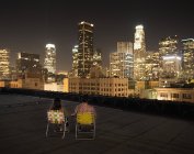 Casal em um telhado com vista para a cidade à noite — Fotografia de Stock