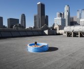 Человек в надувном бассейне на городской крыше — стоковое фото