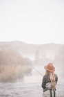 Pescatrice in piedi sulle rive di un fiume — Foto stock