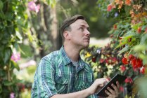 Hombre usando una tableta digital en invernadero - foto de stock