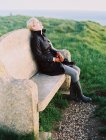 Donna seduta su una panchina di pietra — Foto stock
