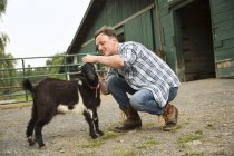 Homem com pequena cabra preta — Fotografia de Stock