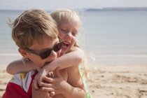 Brother and sister playfighting on the beach. — Stock Photo