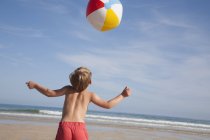 Мальчик играет с пляжным мячом . — стоковое фото