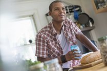 Man in a farmhouse kitchen with a glass — Stock Photo