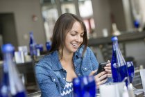 Mujer usando un teléfono inteligente en el restaurante - foto de stock