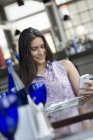 Donna che utilizza uno smartphone nel ristorante — Foto stock
