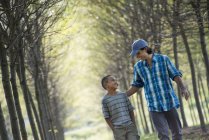 Man and boy walking on avenue of trees. — Stock Photo