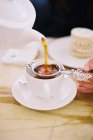Person gießt eine Tasse Tee ein — Stockfoto