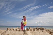 Junge steht neben einer Sandburg — Stockfoto