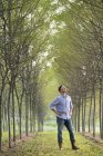 Человек, стоящий на аллее деревьев — стоковое фото
