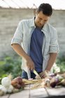 Homme hachant des légumes fraîchement cueillis — Photo de stock