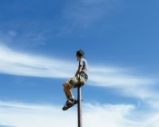 Человек сидит и балансирует на металлическом столбе — стоковое фото