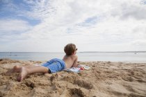 Niño acostado en la arena - foto de stock