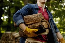 Uomo che trasporta una pila di tronchi — Foto stock