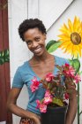 Mujer sosteniendo una gran planta con flores - foto de stock