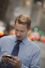 Homem com telefone celular em uma rua movimentada — Fotografia de Stock