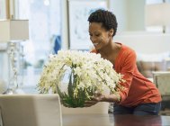 Femme plaçant vase de fleurs — Photo de stock