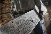 Mann trägt große Holzplanke — Stockfoto