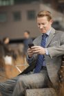 Hombre de negocios mirando un teléfono celular - foto de stock