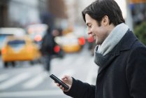 Чоловік зі смартфоном на жвавій вулиці — стокове фото