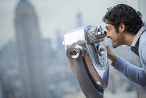Mann blickt durch ein Teleskop über die Stadt. — Stockfoto
