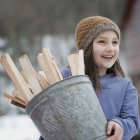 Girl carrying bucket full of kindling — Stock Photo