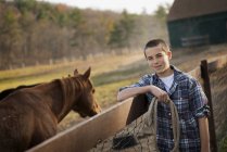 Мальчик, стоящий у лошади паддок . — стоковое фото