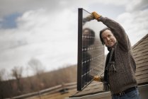 Hombre que lleva el panel solar grande - foto de stock