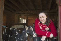 Girl leaning on the barrier of the goat shed — Stock Photo