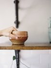 Person reaching up for pottery bowl — Stock Photo