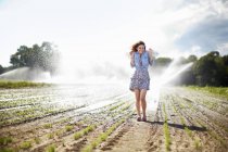 Woman irrigation sprinklers working in the background. — Stock Photo