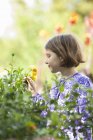 Giovane ragazza che raccoglie fiori in un giardino . — Foto stock