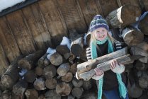 Chica recogiendo leña de la pila de troncos . - foto de stock