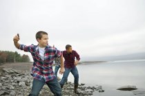 Хлопчики кидають камінці по воді . — стокове фото