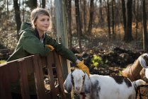 Женщина, стоящая в загоне со стаей коз — стоковое фото